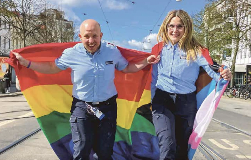 Tågchaufförer springer på gatan med prideflaggan
